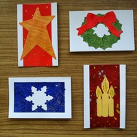 Holiday Gift Tags D: Orange star on red field; wreath with red bow; white snowflake on blue field; yellow candles on speckled red field.