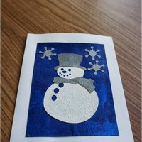 Frosty: white textured snowman, with top hat and scarf, on a shiny blue field with a few silver snowflakes.